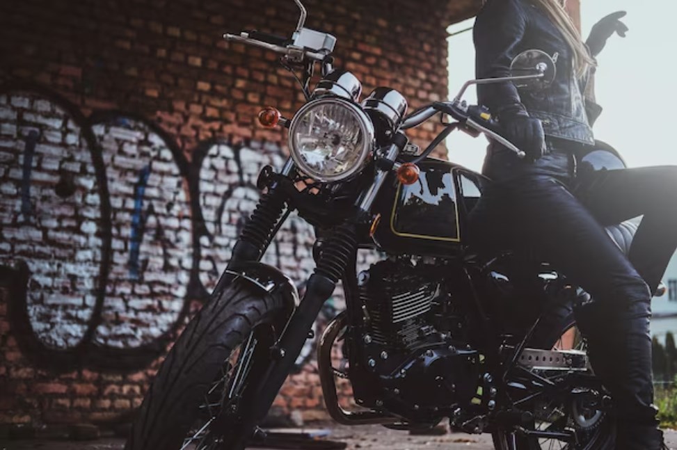 a woman in biker clothing posing while leaning against a motorcycle